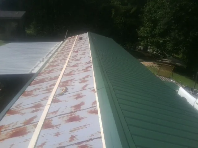 Old rusted panels beside newly installed green metal roofing — Wind Damage Roof Repair by Roofing Brothers in Newhall