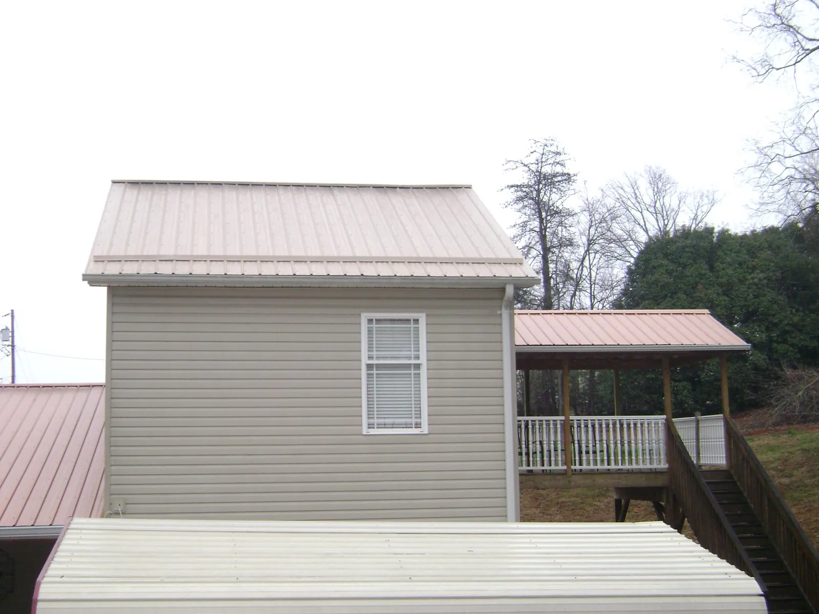 Tan metal roofs on a two story addition and attached porch, from a Roof Replacement job in Newhall