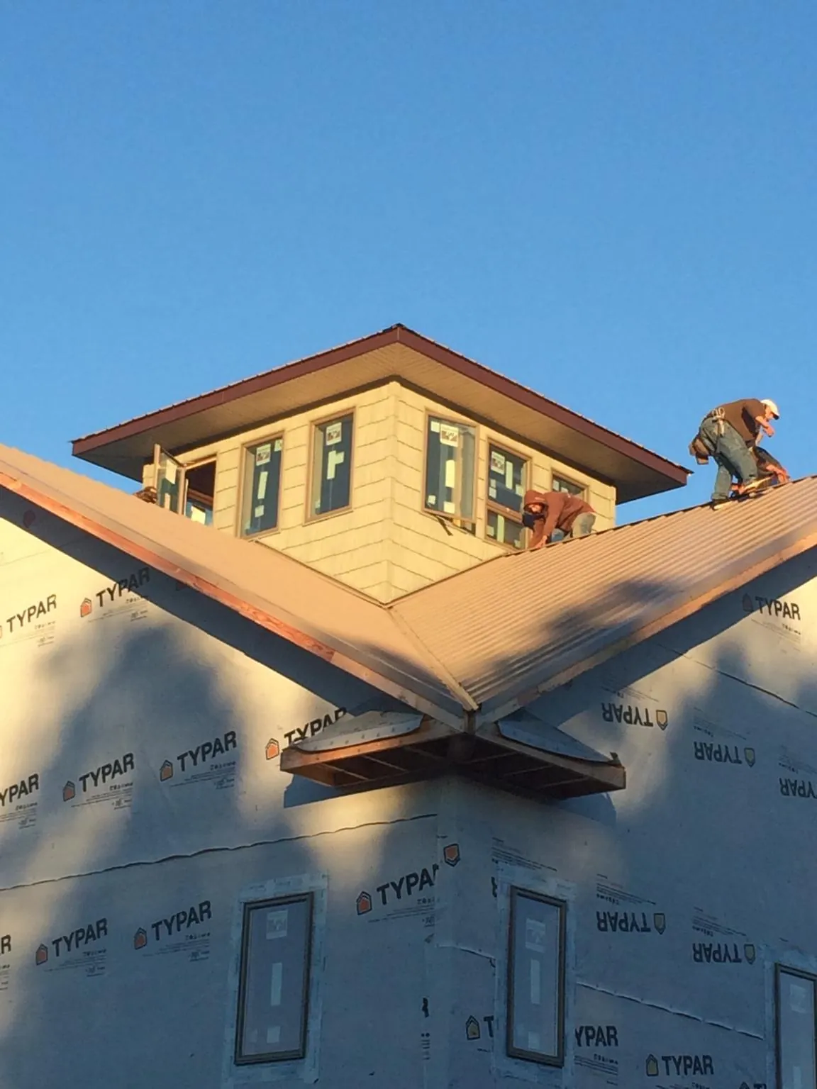 Roofers working around a rooftop cupola on a new metal roof at sunset — Roof Waterproofing in Newhall by Roofing Brothers